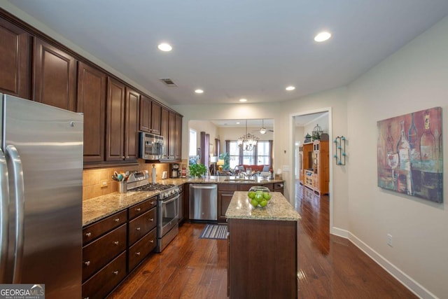 kitchen with appliances with stainless steel finishes, a center island, visible vents, and light stone counters