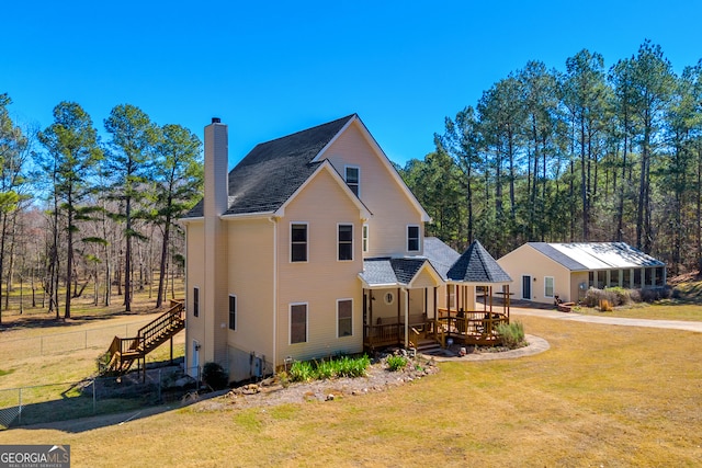 view of front of home featuring stairs, a front lawn, a chimney, and fence