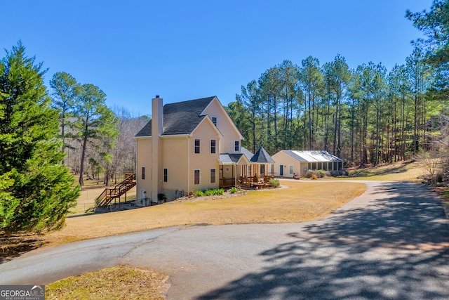 view of home's exterior with a yard, stairway, and a chimney