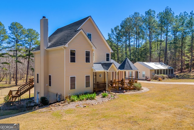 view of front of home with a deck, a chimney, and a front lawn