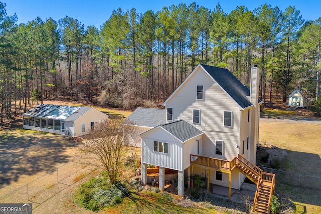 view of front of home with a shingled roof, a chimney, stairway, and a deck