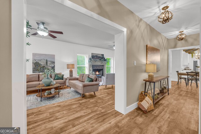 599 Double Branch Rd, Danielsville, GA 30633 - living room featuring a ceiling fan, wood finished floors, a warm lit fireplace, and a chandelier