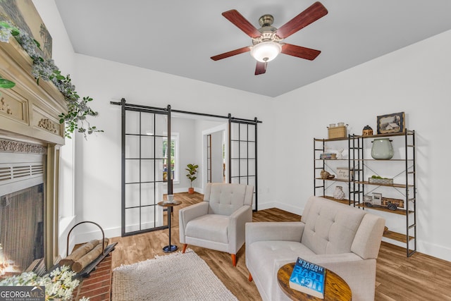 599 Double Branch Rd, Danielsville, GA 30633 - sitting room featuring a barn door, light wood-style floors, ceiling fan, baseboards, and a fireplace