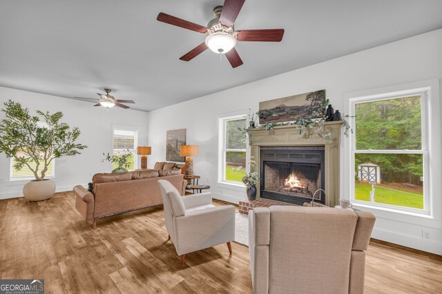 599 Double Branch Rd, Danielsville, GA 30633 - living area with ceiling fan, light wood-type flooring, a lit fireplace, and baseboards