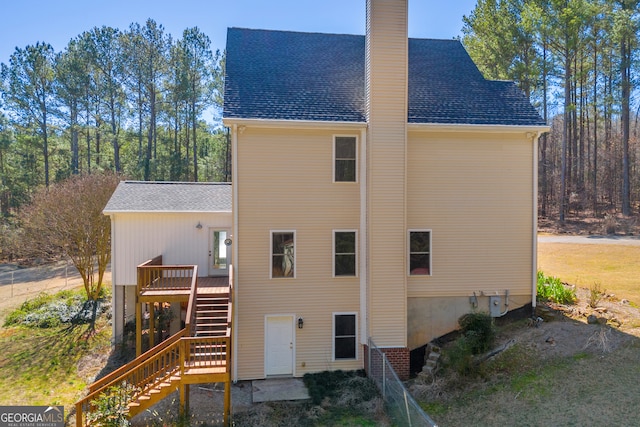 rear view of house with a shingled roof, stairway, a chimney, and a wooden deck