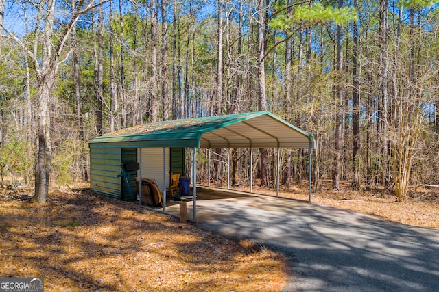 exterior space featuring a carport, driveway, and a view of trees