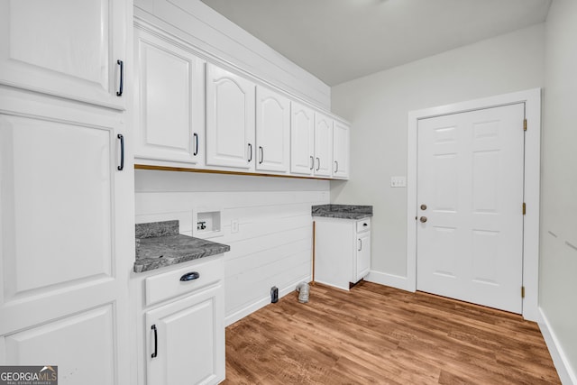 washroom with cabinet space, light wood-style flooring, washer hookup, and baseboards