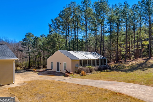 view of front of home with a forest view and a front lawn