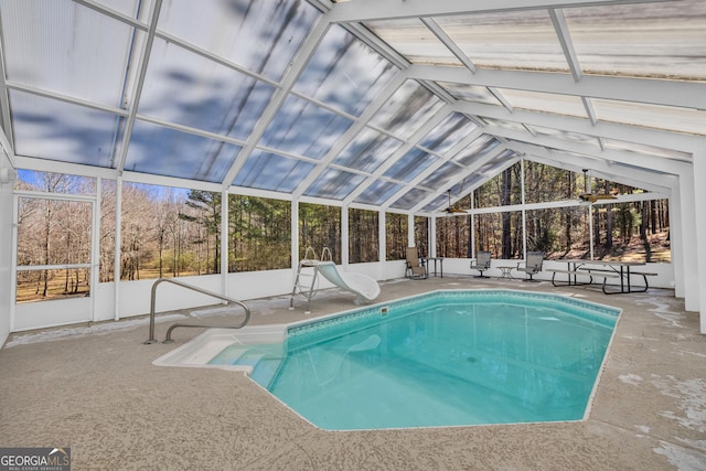 indoor pool featuring a patio area, glass enclosure, and a water slide