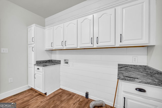 kitchen with visible vents, white cabinetry, wood finished floors, dark stone counters, and baseboards