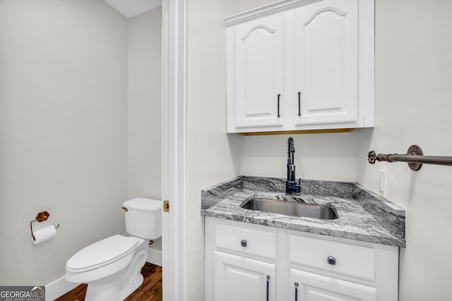 bathroom featuring baseboards, vanity, toilet, and wood finished floors