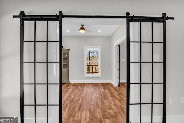 interior space featuring recessed lighting, light wood-style flooring, baseboards, and a barn door