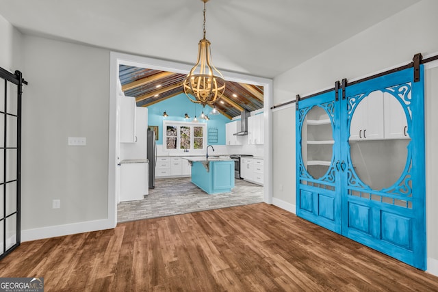 unfurnished dining area featuring lofted ceiling with beams, a barn door, and wood finished floors