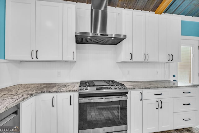 kitchen featuring stainless steel appliances, white cabinets, wall chimney range hood, and light stone countertops