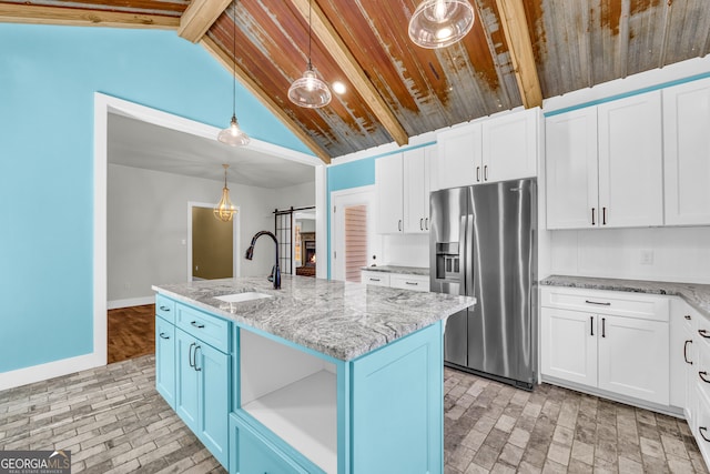 kitchen featuring stainless steel fridge, a barn door, baseboards, white cabinets, and a sink