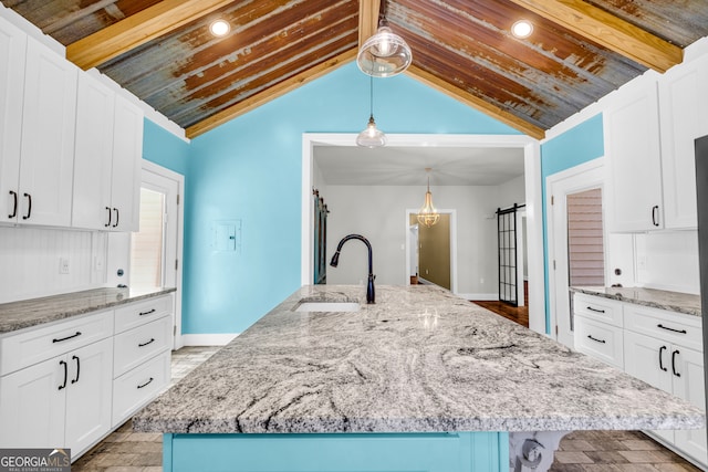 kitchen with light stone counters, white cabinets, and a barn door