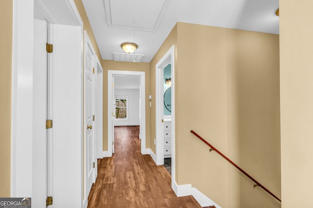 corridor featuring attic access, baseboards, visible vents, wood finished floors, and an upstairs landing