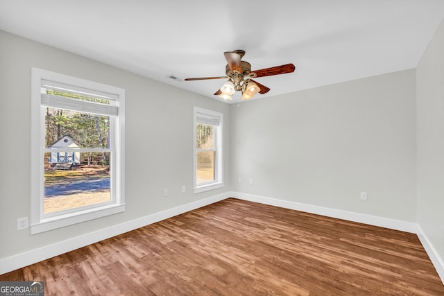 unfurnished room with wood finished floors, a ceiling fan, and baseboards