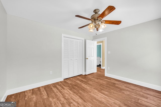 unfurnished bedroom featuring a ceiling fan, a closet, baseboards, and wood finished floors