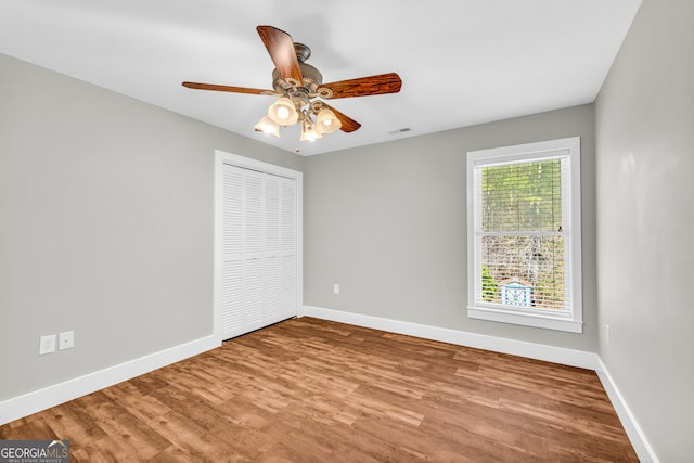 unfurnished bedroom featuring a closet, visible vents, baseboards, and wood finished floors