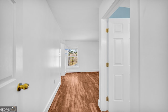 corridor with baseboards and wood finished floors