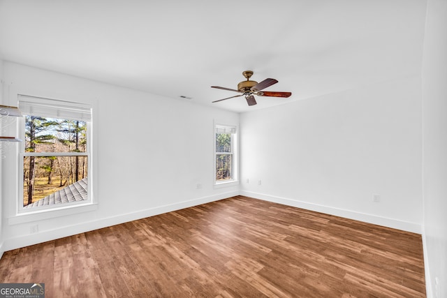 unfurnished room with a ceiling fan, visible vents, baseboards, and wood finished floors