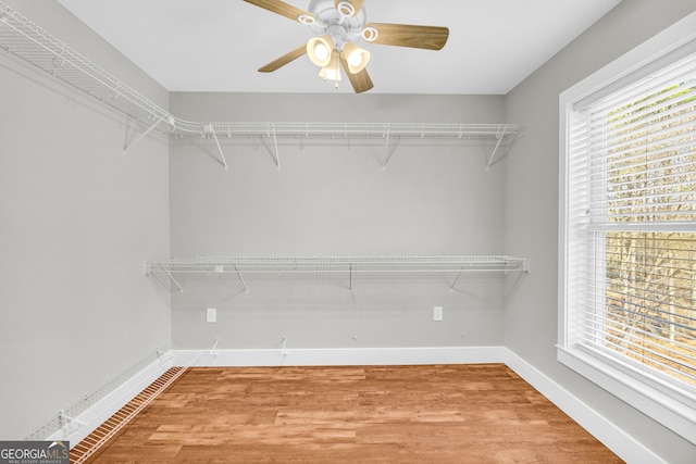 walk in closet with light wood-style floors and ceiling fan