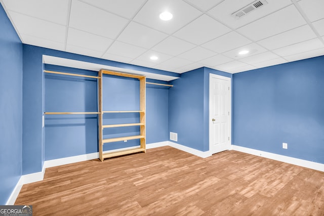 unfurnished bedroom featuring a drop ceiling, wood finished floors, visible vents, and baseboards