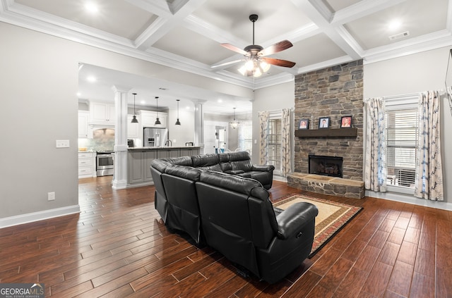 living room featuring a stone fireplace, dark wood-style flooring, coffered ceiling, and visible vents