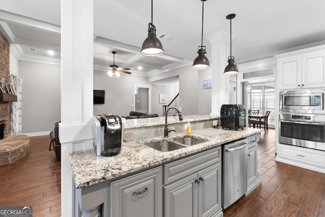 kitchen with visible vents, dark wood-style floors, appliances with stainless steel finishes, a stone fireplace, and a sink