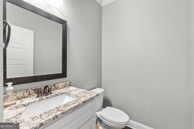 half bathroom with baseboards, vanity, and toilet