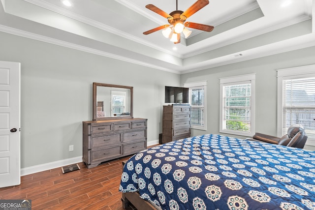 bedroom featuring baseboards, a raised ceiling, ceiling fan, dark wood-type flooring, and crown molding