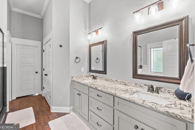 full bath featuring ornamental molding, double vanity, a sink, and wood finished floors