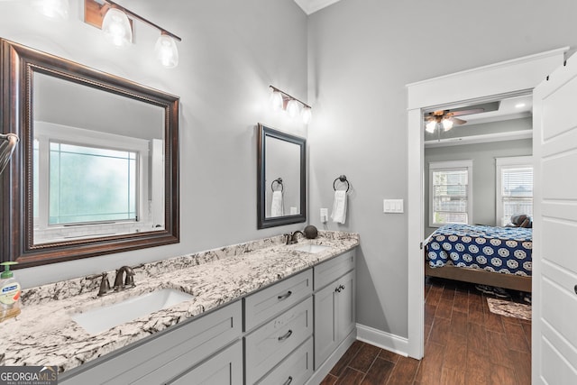 ensuite bathroom featuring connected bathroom, baseboards, a sink, and wood finish floors