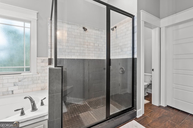 bathroom featuring wood finish floors, a stall shower, a garden tub, and toilet