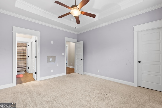 unfurnished bedroom with carpet, a tray ceiling, baseboards, and ornamental molding