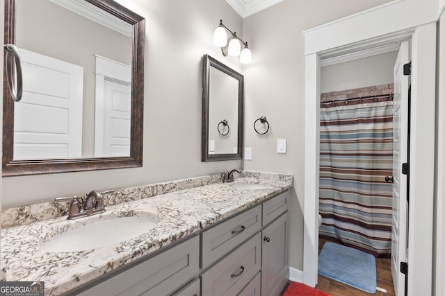 full bathroom featuring wood finished floors, double vanity, ornamental molding, and a sink