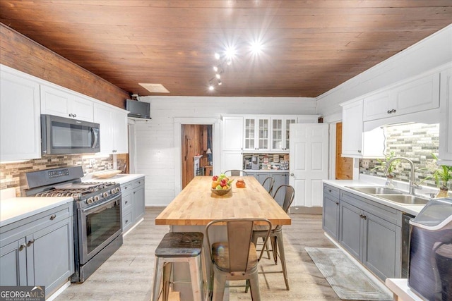 kitchen featuring wooden ceiling, a sink, stainless steel range with gas stovetop, and gray cabinetry