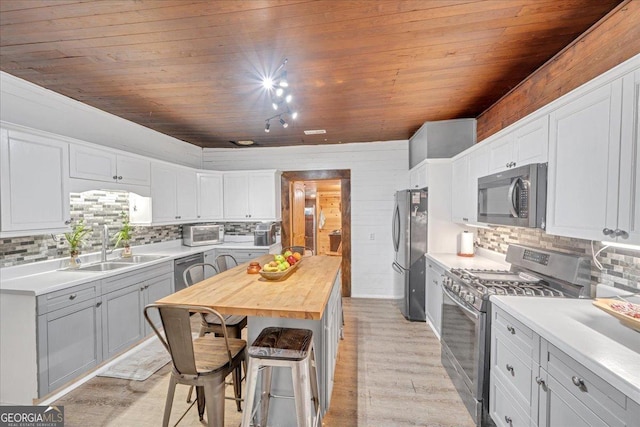 kitchen featuring appliances with stainless steel finishes, butcher block countertops, a sink, and wood ceiling