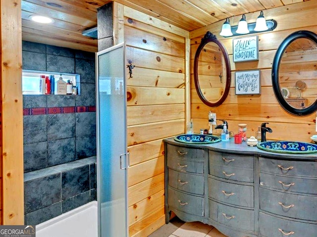 bathroom featuring wooden ceiling, wooden walls, a sink, a shower stall, and double vanity