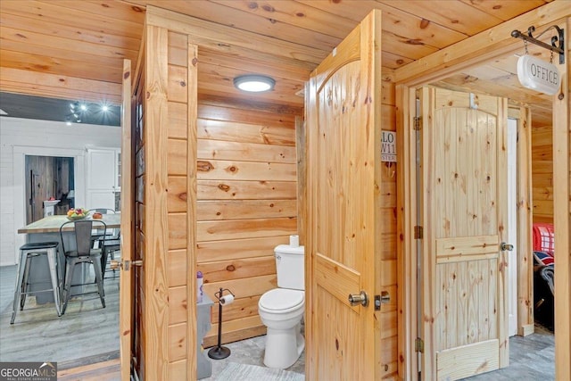 bathroom with wooden ceiling, wood walls, and toilet