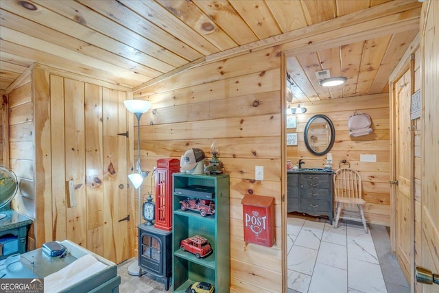 recreation room featuring marble finish floor, wood walls, wooden ceiling, and a sink