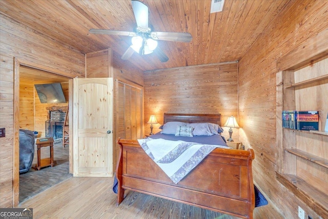 bedroom featuring wooden walls, visible vents, wooden ceiling, ceiling fan, and wood finished floors