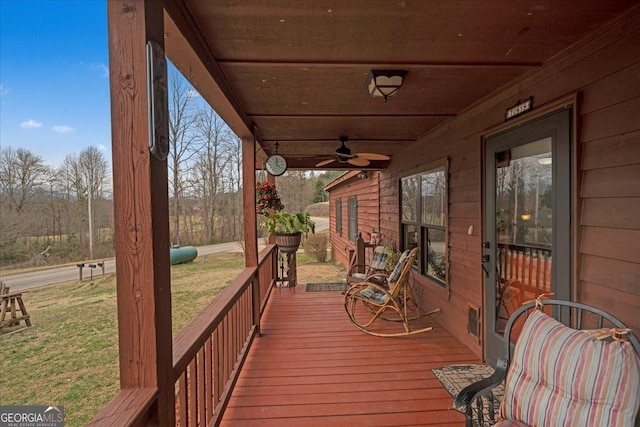 wooden deck with ceiling fan and a yard