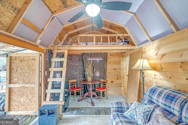 interior space featuring a ceiling fan, vaulted ceiling, and wooden walls