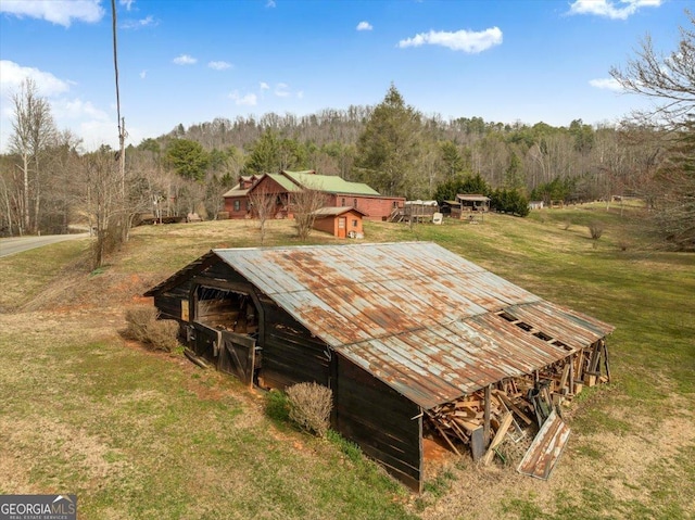 exterior space featuring a yard, an outbuilding, a view of trees, and an outdoor structure