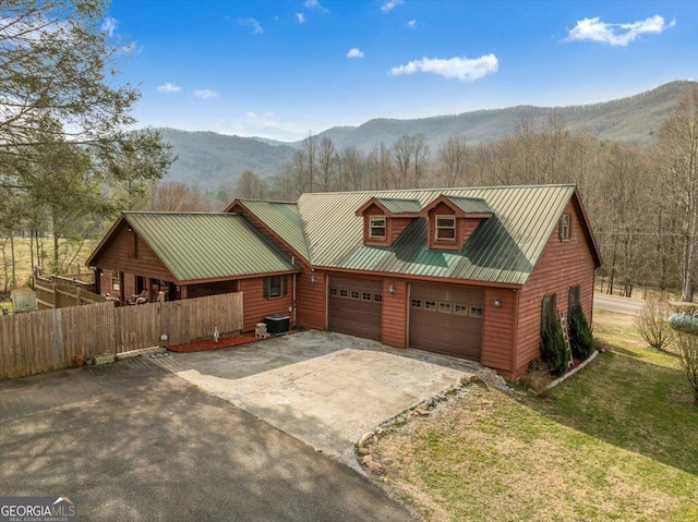 rustic home with metal roof, cooling unit, a mountain view, fence, and concrete driveway