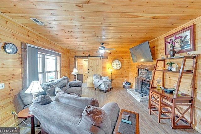 living room with wooden ceiling, a barn door, a fireplace, and wood finished floors