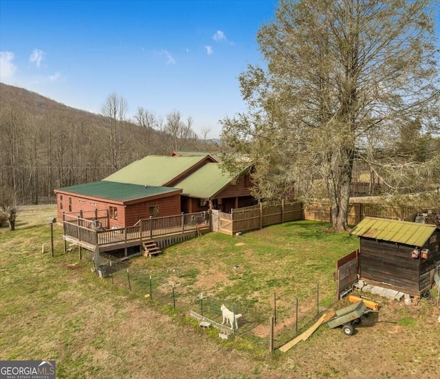 exterior space with a deck, metal roof, a yard, and a wooded view