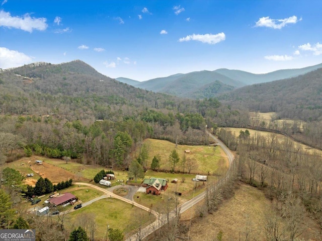 aerial view with a mountain view, a view of trees, and a rural view